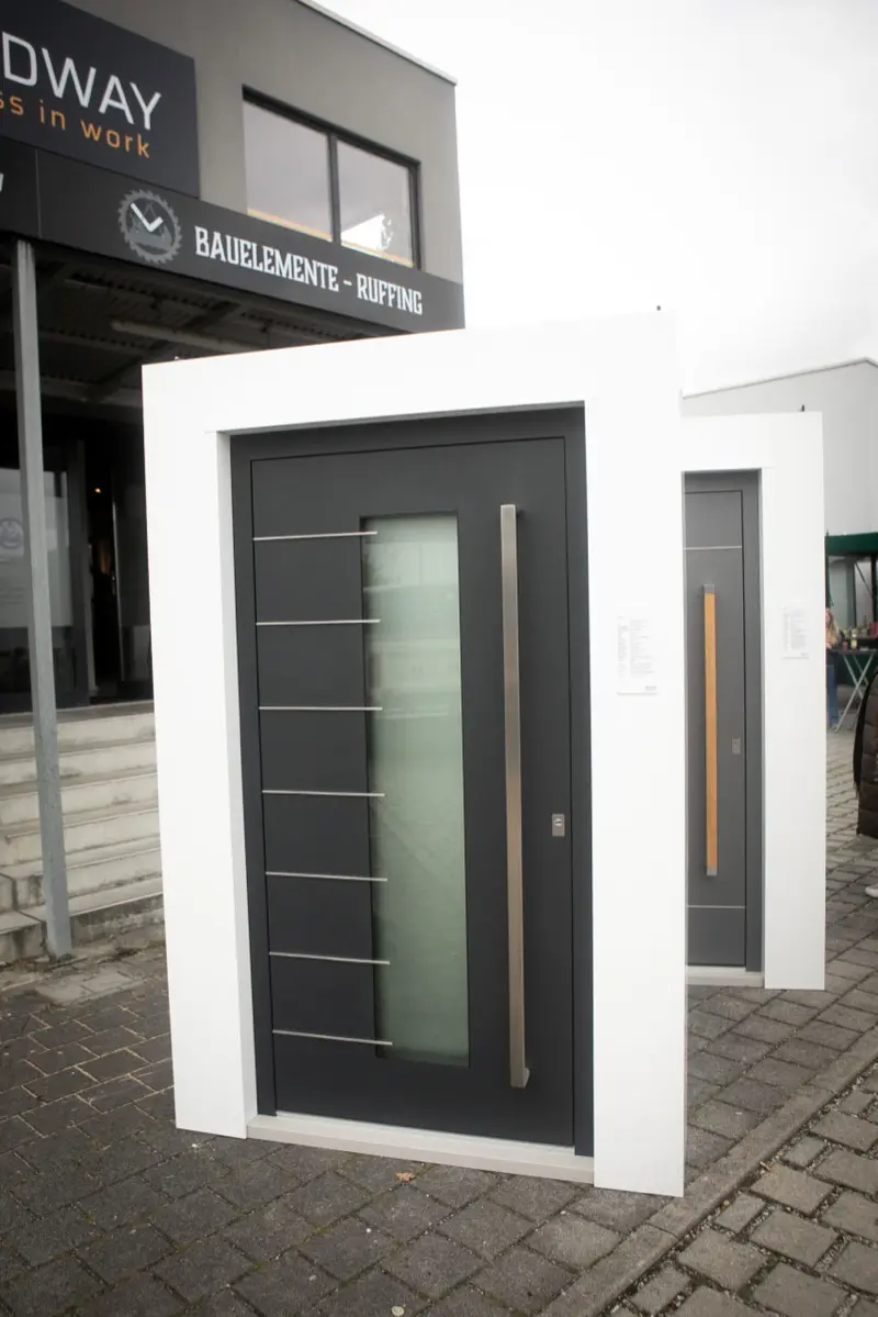 Moderne anthrazitfarbene Haustüren mit Edelstahlgriff, ausgestellt vor dem Showroom von Bauelemente Ruffing